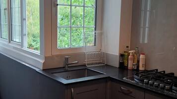 A modern kitchen with a window, a sink, cabinets, and a stove.