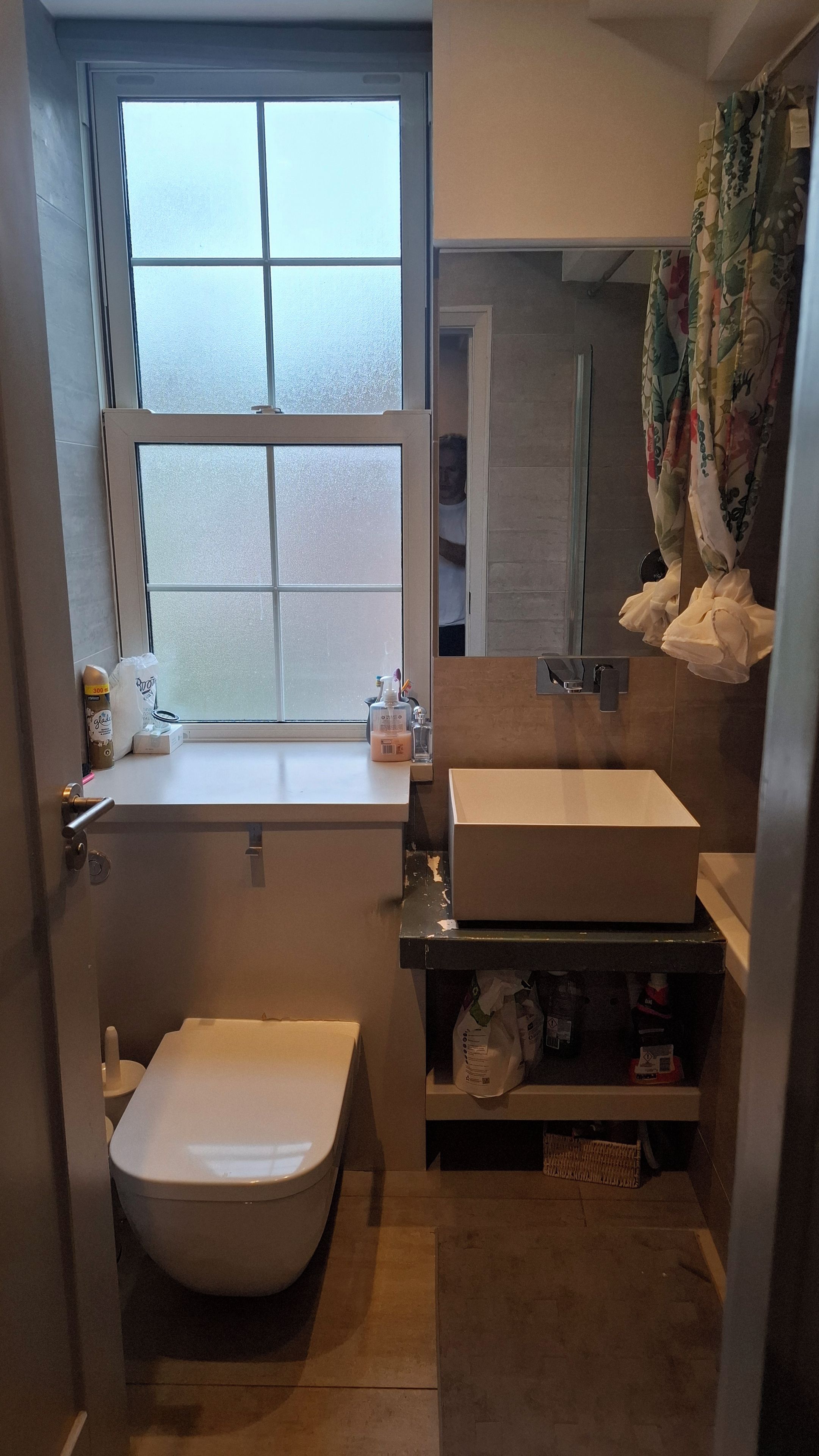 A compact bathroom with a toilet, a sink, and a window.