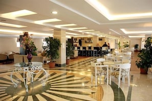 Un vestíbulo de hotel con suelo a cuadros, zonas de estar y una mesa de recepción.