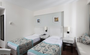 Habitació d'hotel amb dos llits individuals, un escriptori petit, una cadira i un sofà.