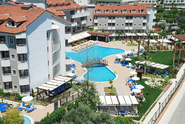 A hotel with a swimming pool, outdoor seating, and a garden area. - Monachus Hotel and Spa - All Inclusive (Manavgat)