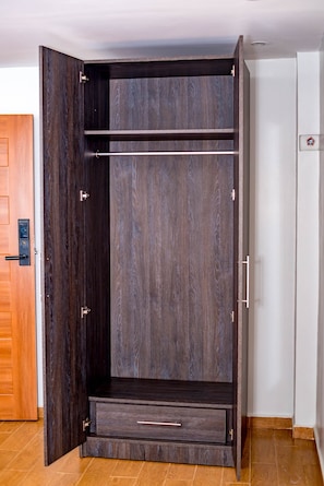 Un armario con acabado en madera oscura, puerta corredera y un cajón pequeño.