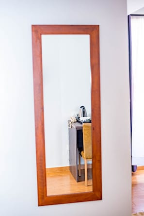 Una habitación con un espejo de madera que refleja un escritorio con un hervidor y una silla.