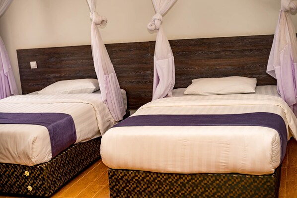 Two beds with canopy-style headboards, a wooden headboard, and a checkered floor.