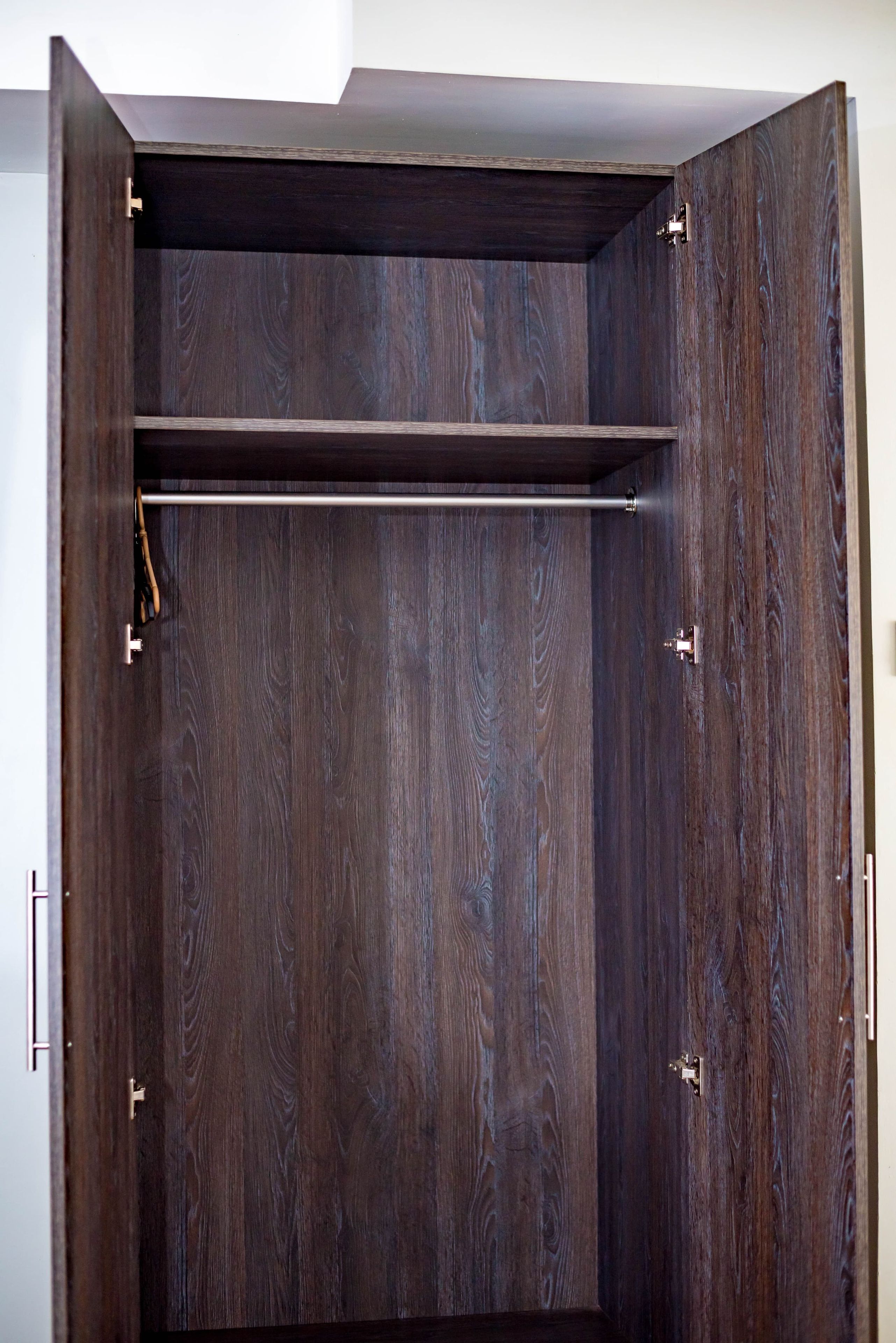 A dark wooden wardrobe with a single shelf and a hanging rod.