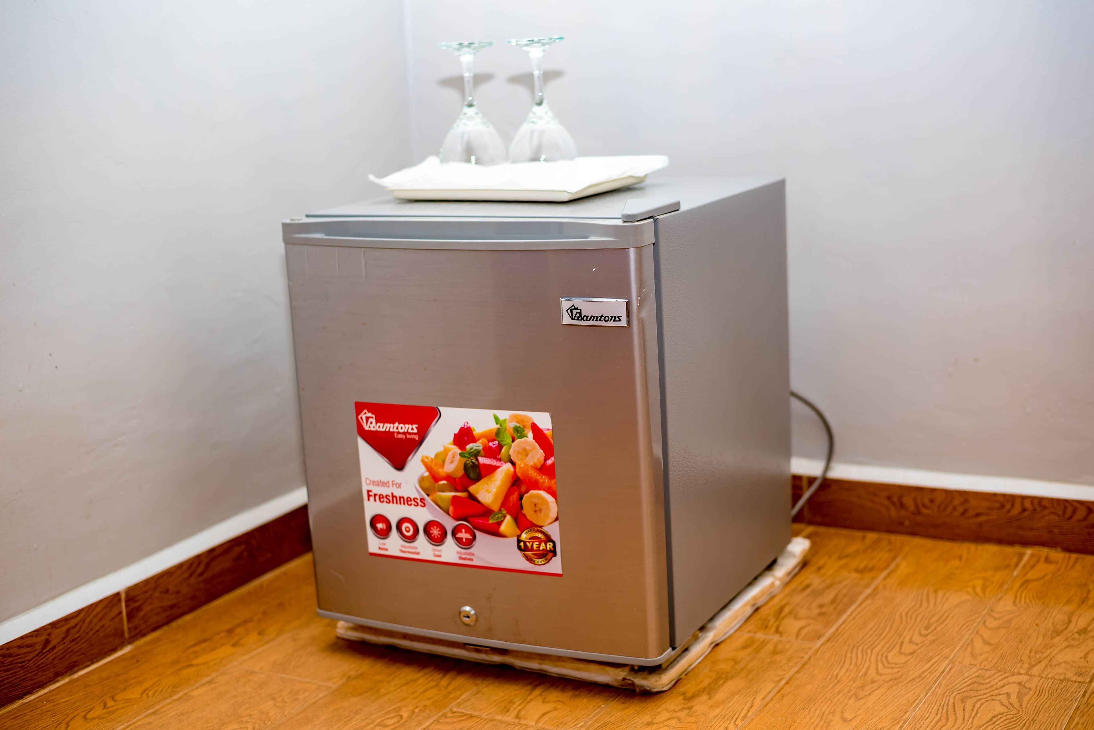 A compact refrigerator with a fresh produce display, a water dispenser, and a brand logo.
