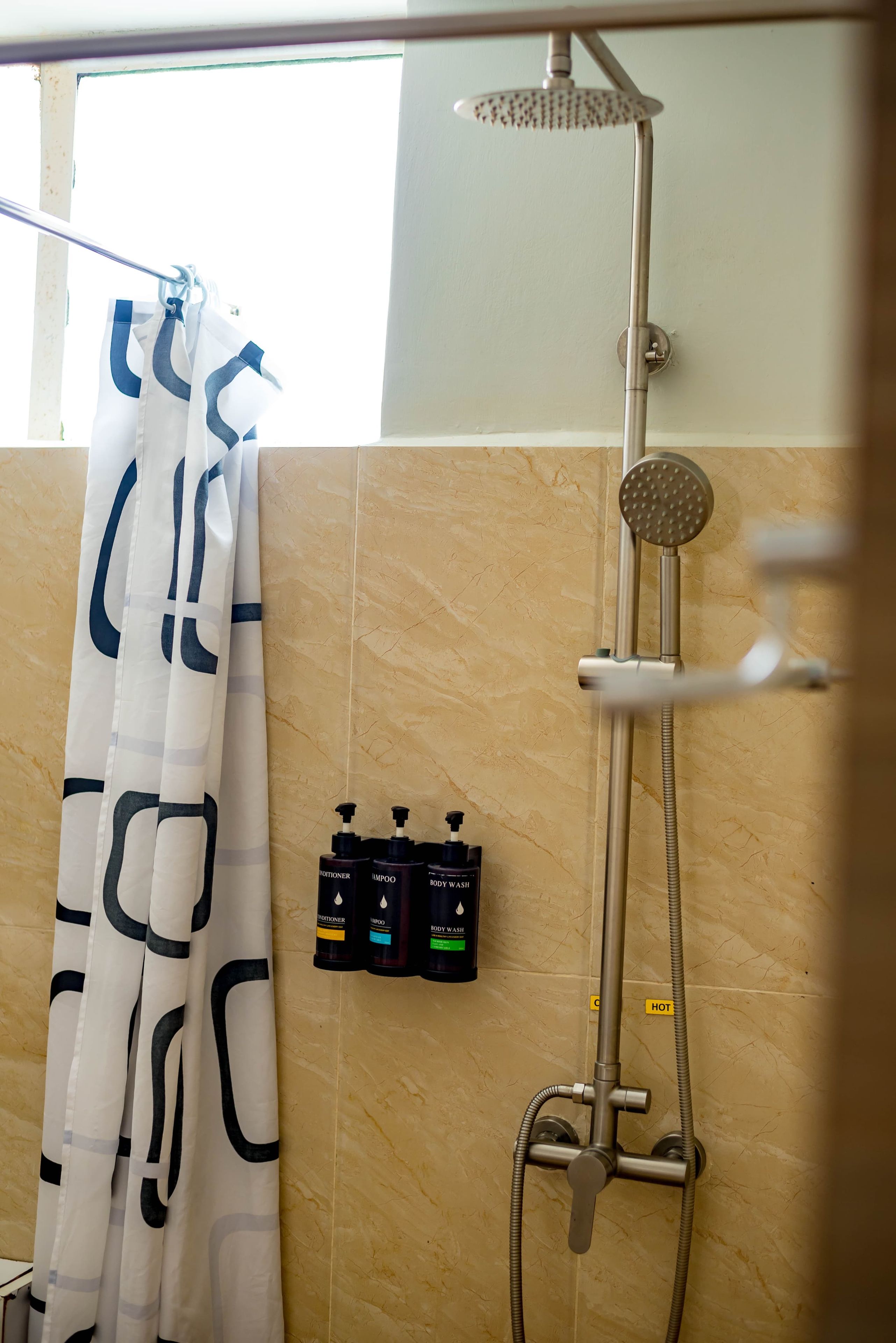 Un baño con ducha, perchero y artículos de aseo.