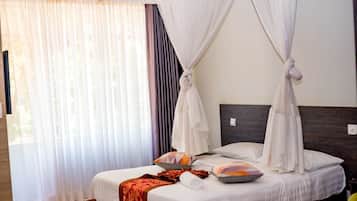 Habitación de hotel con cama, dosel, ventana con cortinas y vista al exterior.