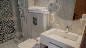 Une salle de bain équipée d’une douche, de toilettes, d’un lavabo et d’un miroir.
