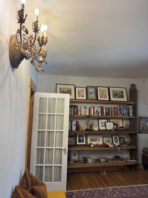 A room with a chandelier, a bookshelf filled with books and framed pictures, a door with a window, and a patterned rug. - Private Downtown Toronto Apartment in the Annex with Free Parking (Toronto)