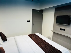 Una habitación de hotel con una cama, un televisor en la pared y una puerta.