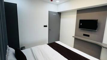 Quarto de hotel moderno com cama, TV de tela plana na parede, ventilador de teto e porta.