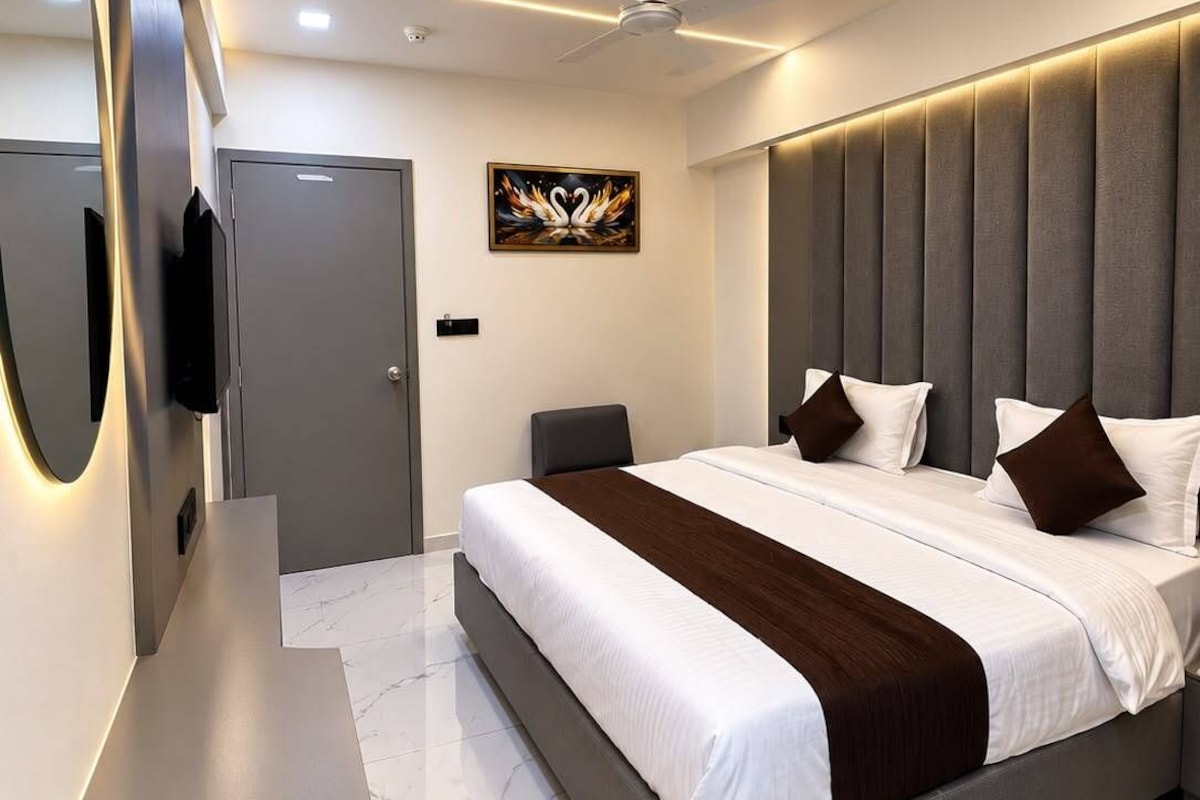 Un dormitorio moderno con una cama grande, un televisor de pantalla plana montado en la pared y un ventilador de techo.