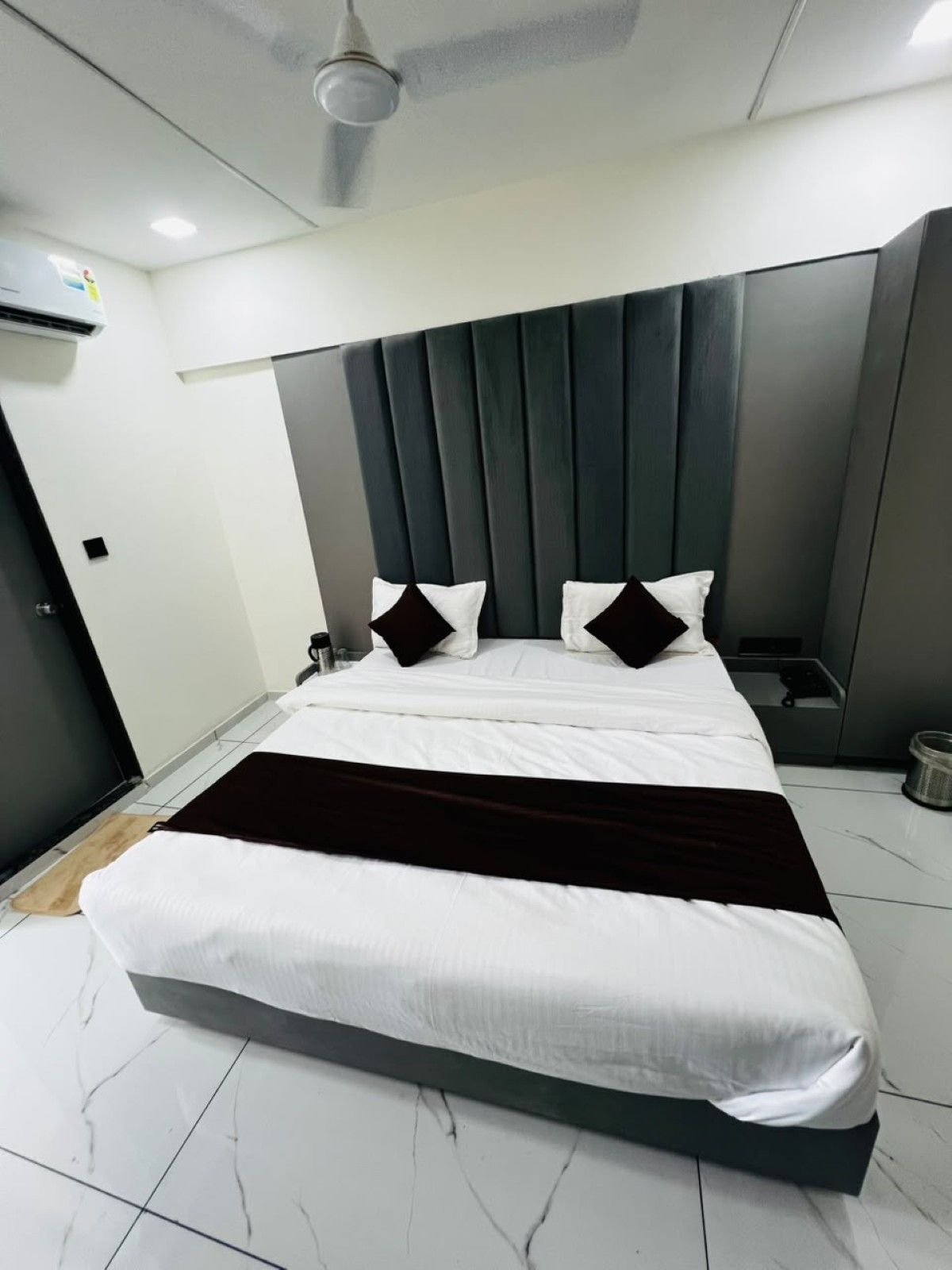 A modern bedroom with a large bed, a dark headboard, and a ceiling fan.