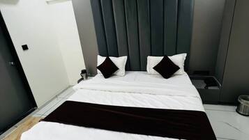 Een moderne slaapkamer met een groot bed, een donker hoofdbord en een plafondventilator.