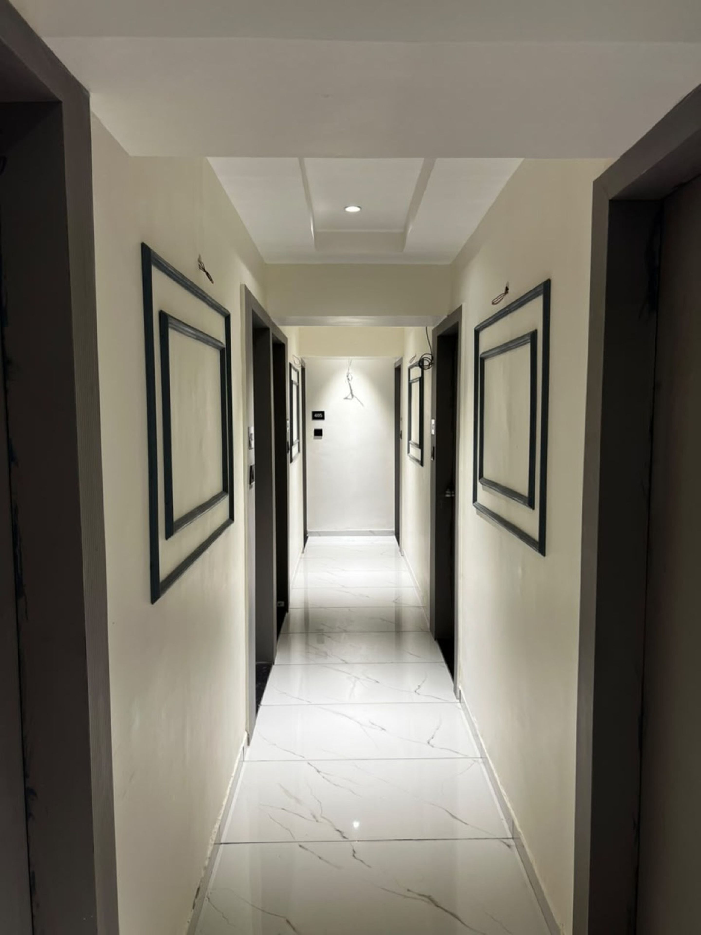 A corridor with a polished marble floor and framed pictures on the walls.