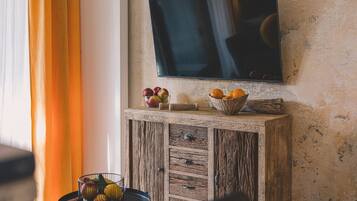 Un mueble de madera rústica con un televisor montado encima, un cuenco de frutas y una pequeña mesa con una cesta de frutas.