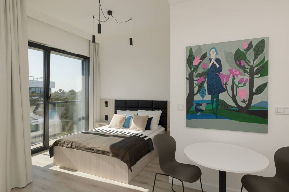 Ein modernes Schlafzimmer mit einem großen Bett, einem runden Tisch und einem Bild an der Wand.