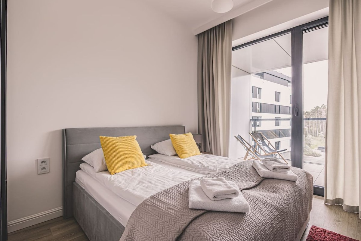 Ein modernes Hotelzimmer mit einem großen Bett, Blick auf die Stadt und einem Balkon.
