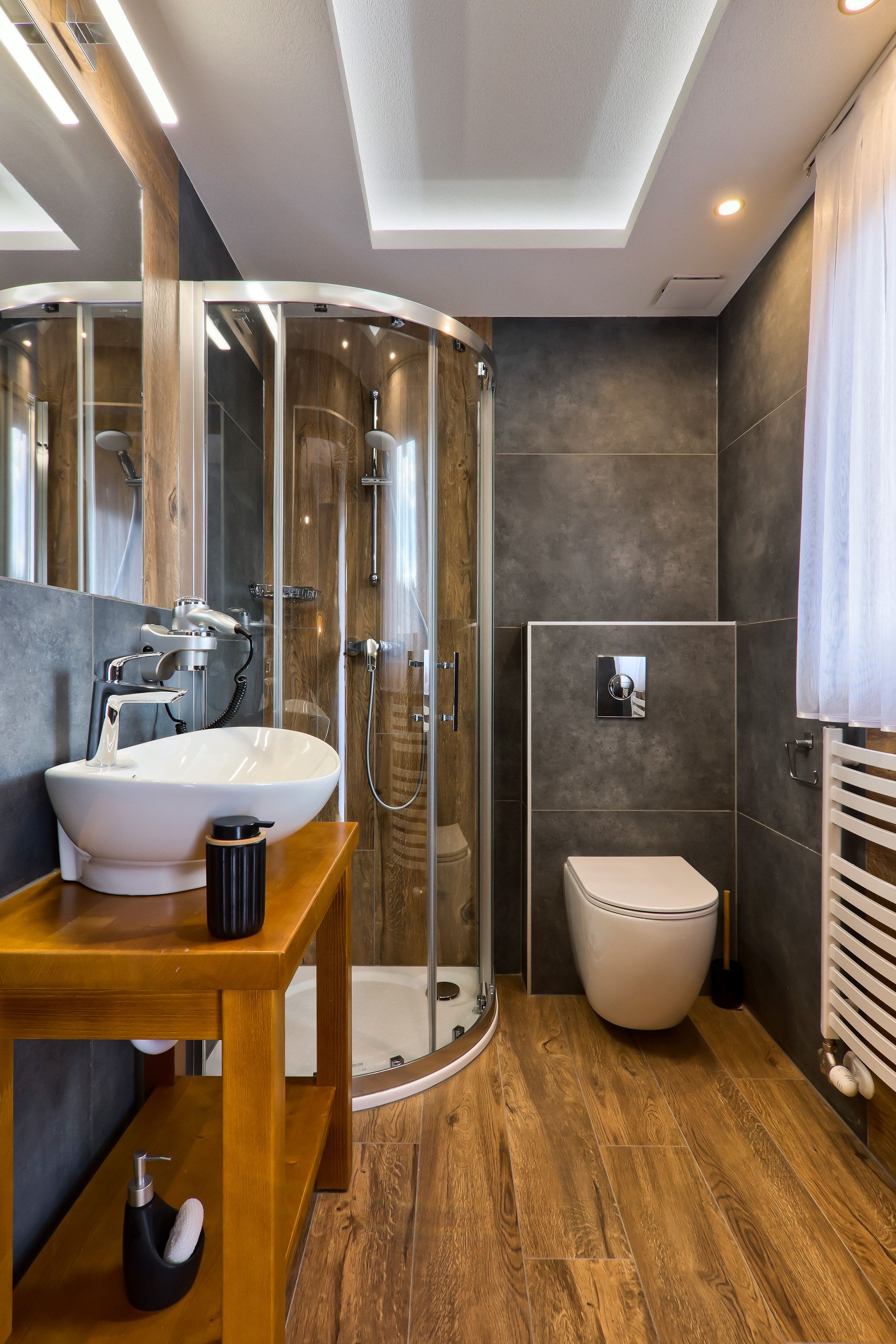 Un baño moderno con ducha de vidrio, un lavamanos blanco y un inodoro.