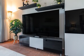 A modern living room with a flat-screen TV, a potted plant, and a floor lamp. - El Rincon del Golf II - Isla Canela Golf GRHII54P57 (Ayamonte)