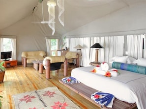 A tented accommodation with a bed, seating area, and a television. - Sau Bay Resort and Spa (Na Sau Bay)