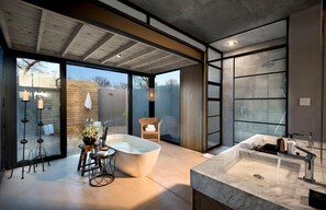 Un baño moderno con una bañera independiente, un lavabo de mármol y una cabina de ducha con mampara de vidrio.