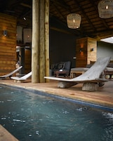 Un área de piscina con sillones de descanso y pilares de madera.
