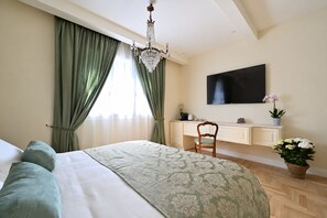 Ein Hotelzimmer mit Bett, Schreibtisch, Fernseher und einer Kristallleuchtre.
