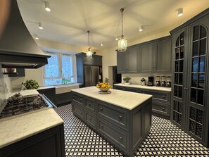 A modern kitchen with dark cabinetry, a central island, and a patterned floor. - Your Private Tuscan Villa 17 Min to Florence · Private Pool · 6 Suites · 7 Baths (Firenze)