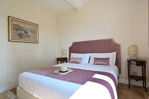 A neatly made bed with a headboard, two bedside tables, and a painting on the wall. - Your Private Tuscan Villa 17 Min to Florence · Private Pool · 6 Suites · 7 Baths (Firenze)