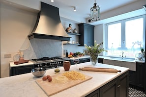 A modern kitchen with a central island, a stove, and a large window. - Your Private Tuscan Villa 17 Min to Florence · Private Pool · 6 Suites · 7 Baths (Firenze)