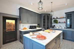 A kitchen with a large island, dark cabinetry, a wine fridge, and a patterned floor. - Your Private Tuscan Villa 17 Min to Florence · Private Pool · 6 Suites · 7 Baths (Firenze)