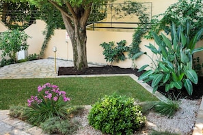 A landscaped garden with a tree, various shrubs, and a well-maintained lawn. - Konstantinos Hotel (Lefkada)