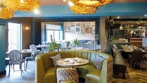 A restaurant interior with a green booth seating area, round tables, and a bar counter. - Gailes Restaurant Hotel (Irvine)