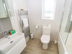 A bathroom with a white sink, toilet, and shower area. - 74 Porthmeor (Redruth)
