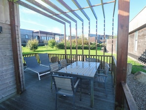 An outdoor patio with a wooden pergola, a table, and several chairs. - 74 Porthmeor (Redruth)