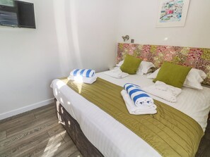 A neatly made bed with white linens, a green headboard, and two pillows. - 74 Porthmeor (Redruth)