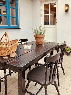 Ein Holztisch mit Stühlen, ein Korbwäschekorb, ein Blumentopf und Kerzen.