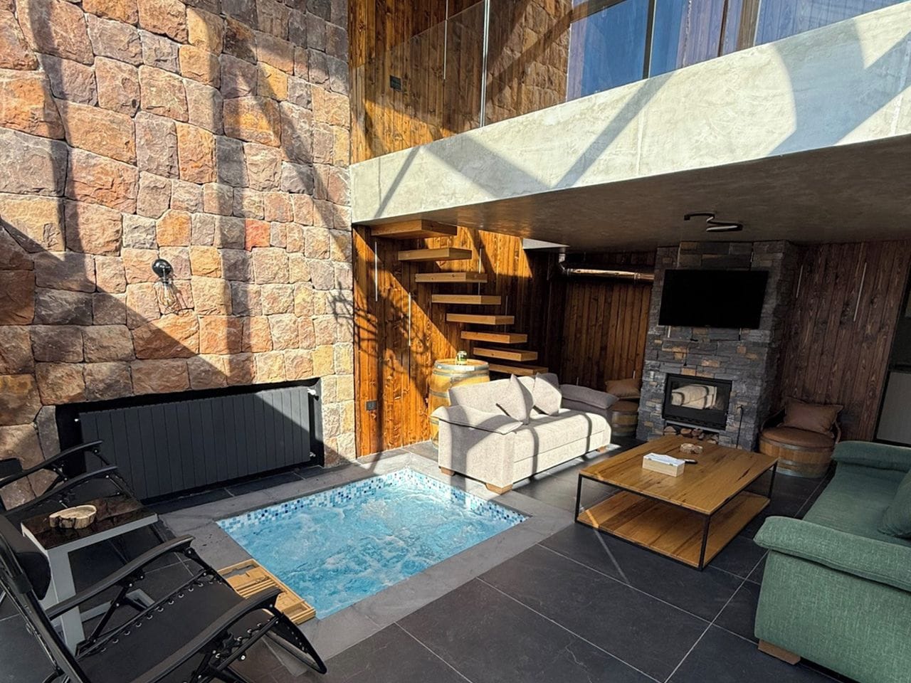 Un espacio exterior moderno con piscina, mobiliario y chimenea.