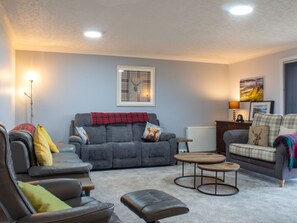 A cozy living room with a grey sofa, a brown leather chair, and a small coffee table. - Skeabost Bungalow by Interhome (Mid Skye)