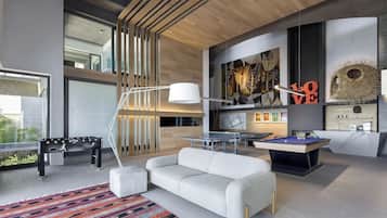 Un espacio habitable moderno con sofá, mesa de ping pong y mesa de billar.