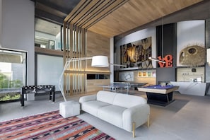 Un espace de vie moderne comprenant un canapé, une table de ping-pong et un billard.