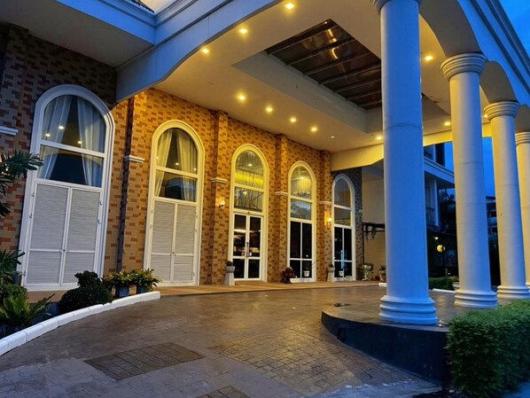 A building with a covered entrance, large arched windows, and a paved courtyard. - Bright Hotel Khon Kaen (Khon Kaen)