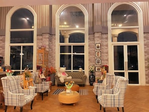 A cozy living room with large arched windows, a plush sofa, and plaid-patterned chairs. - Bright Hotel Khon Kaen (Khon Kaen)