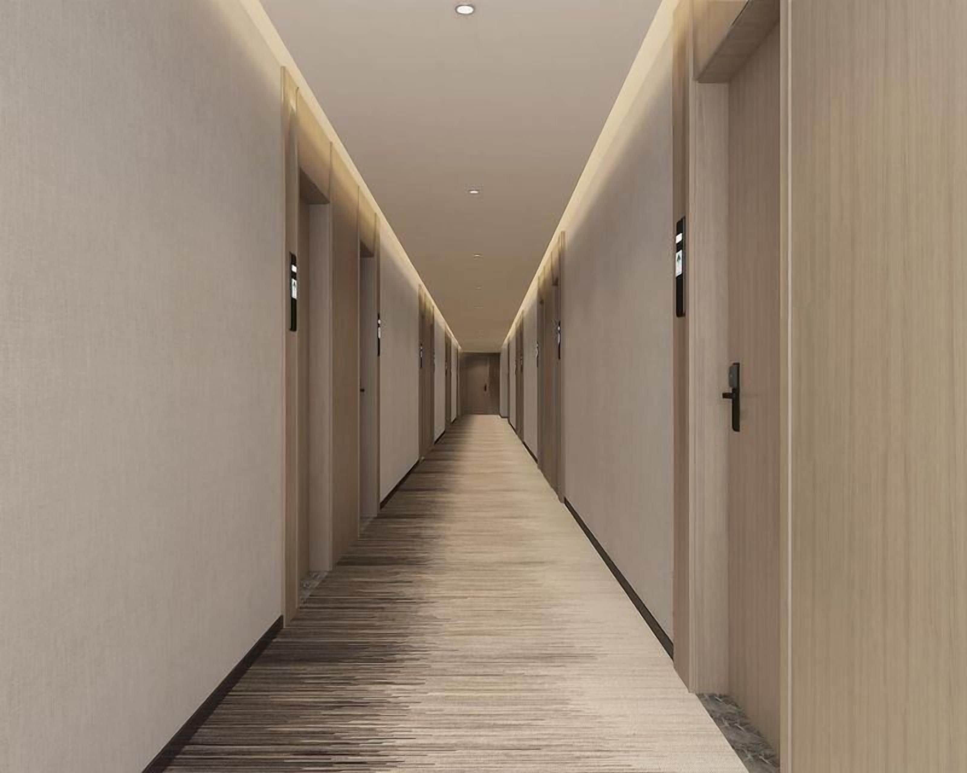 A long, narrow hallway with doors on both sides, leading to individual rooms.