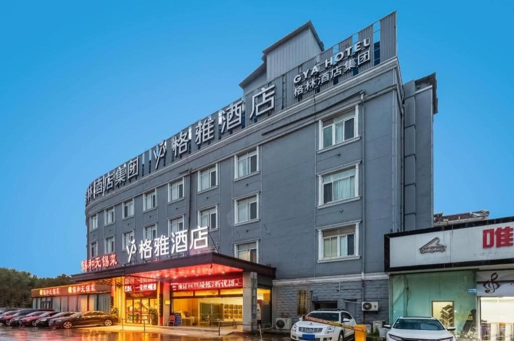 A hotel with multiple floors, a prominent sign, and a parking lot with cars.