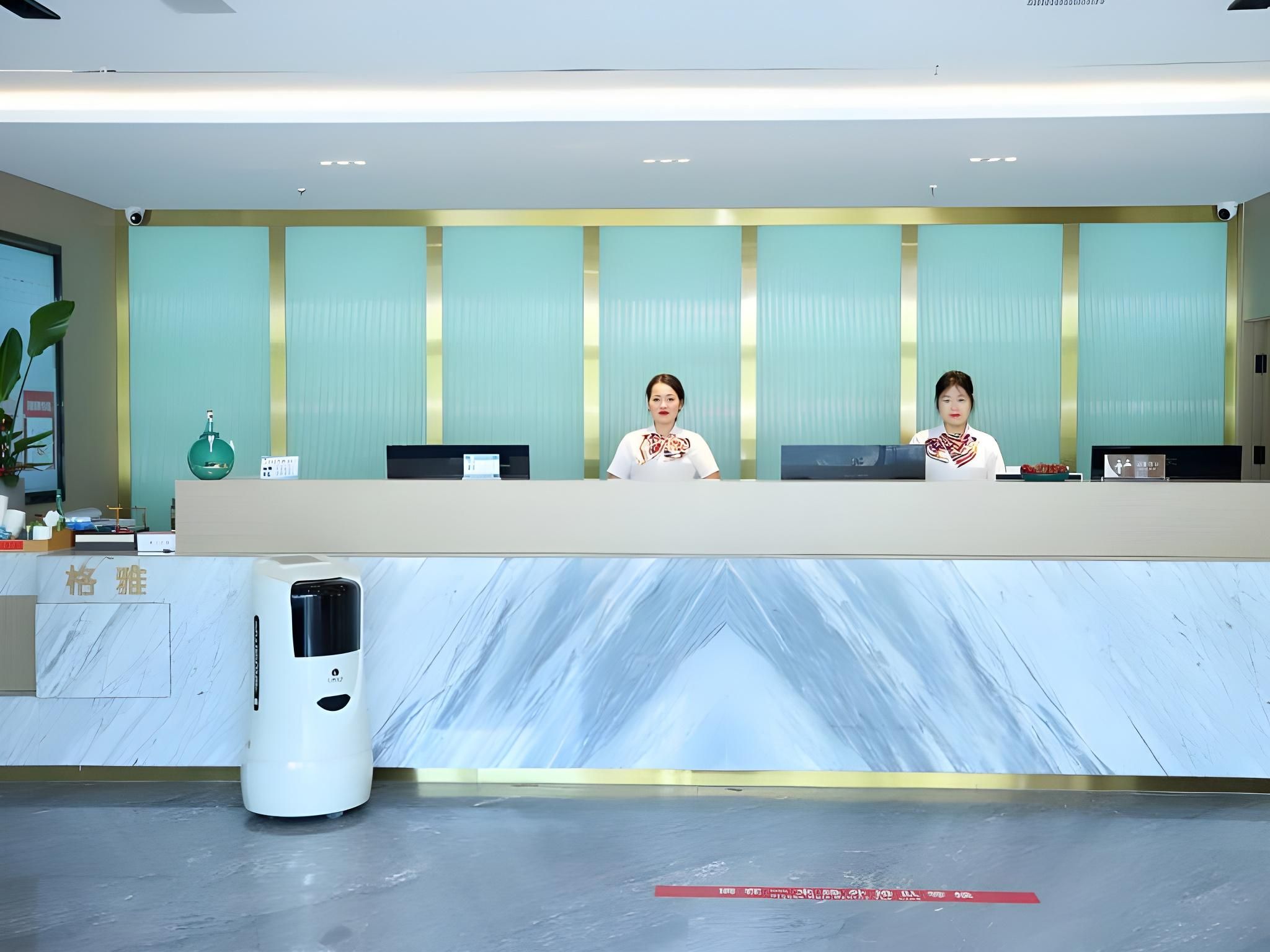 A reception desk with two staff members, a marble counter, and a trash bin.