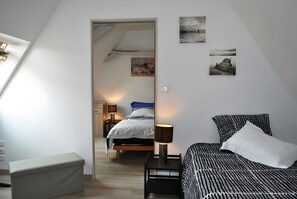 A bedroom with a bed, bedside table, lamp, and a view of another room through an open door. - Cottage 'La Grange Soleil' with Private Terrace, Wi-Fi and Air Conditioning (Veigné)