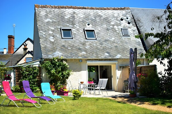 A house with a sloped roof, a small patio with outdoor furniture, and a garden area.